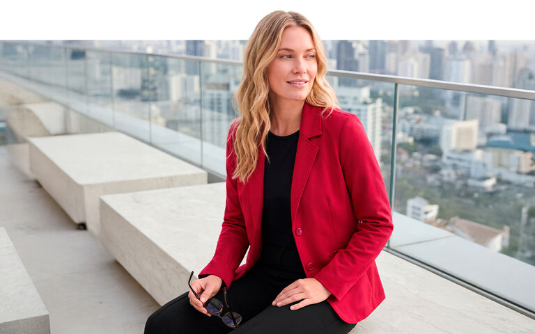 Vrouw in een rode blazer tegen een skyline